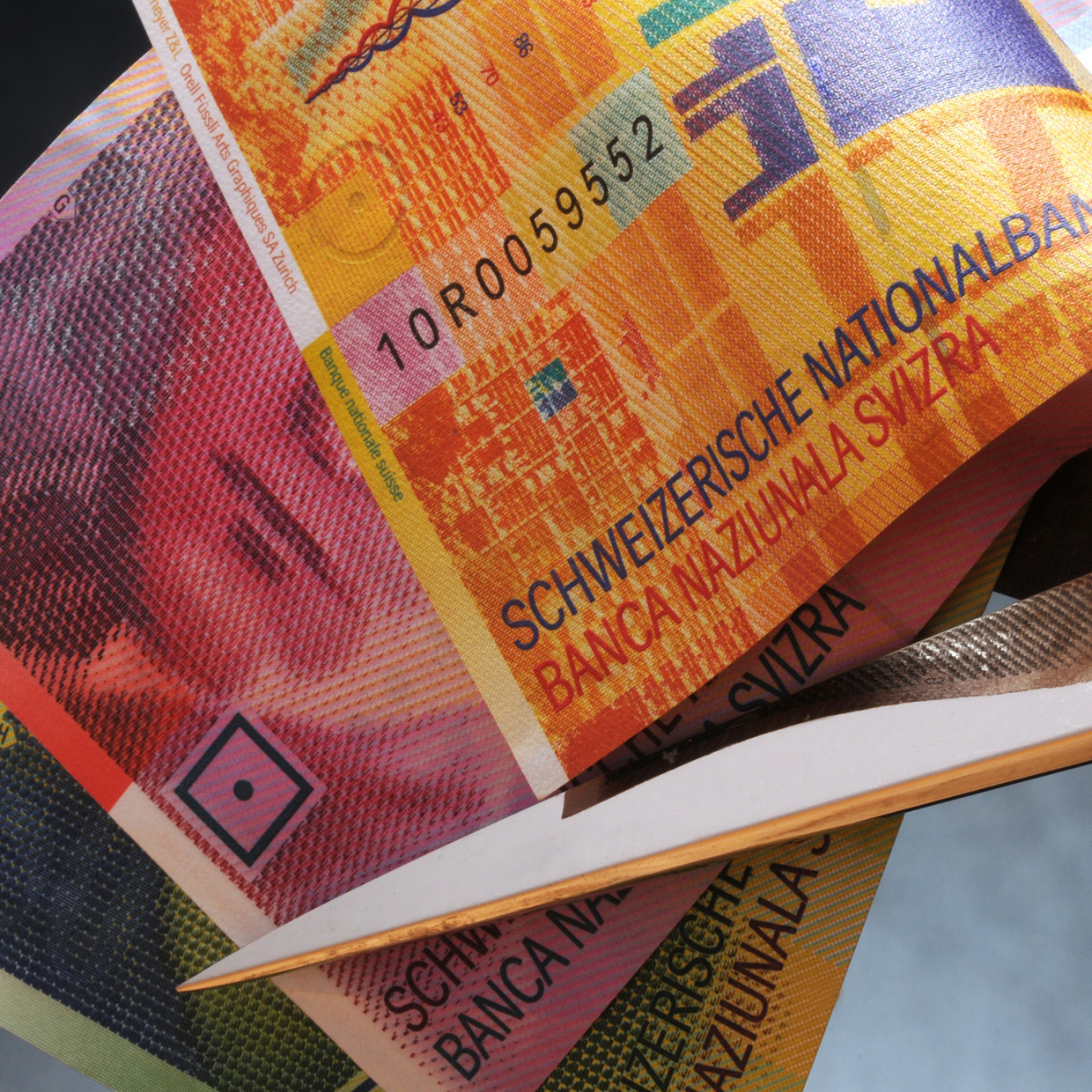 Eine Schere setzt an Schweizer Banknoten an